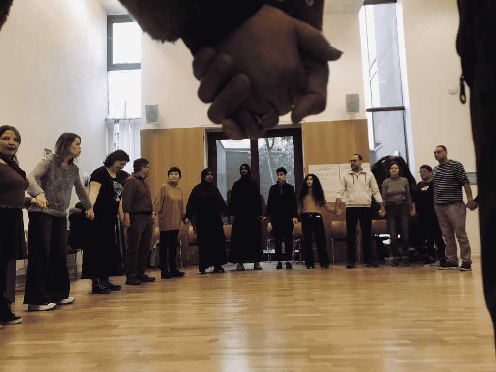 A photo of a large group of people holding hands standing in a circle